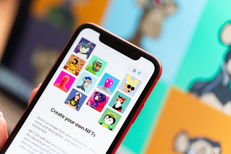 A person holds a smartphone displaying a gallery of colorful digital cartoon characters, suggesting the creation of NFTs. The background features blurred artwork, emphasizing the digital and creative theme.