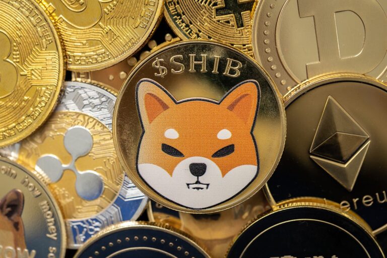 Various cryptocurrency coins are shown, featuring Shiba Inu prominently in the center with its dog logo on a gold coin. Surrounding coins include Bitcoin, Ethereum, and Ripple, displaying their distinct logos.